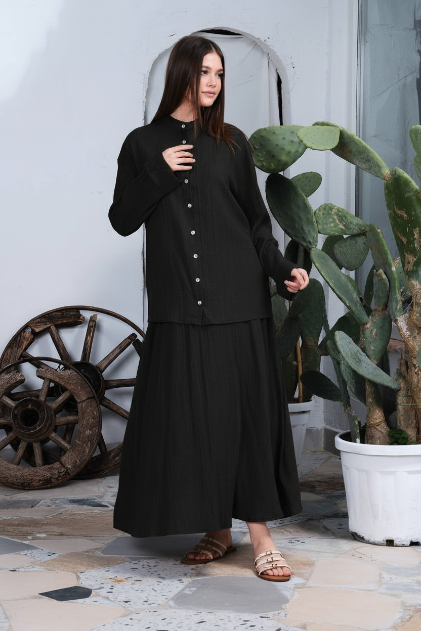 Model wearing a black 50% cotton 50% viscose shirt and matching fluid maxi skirt set